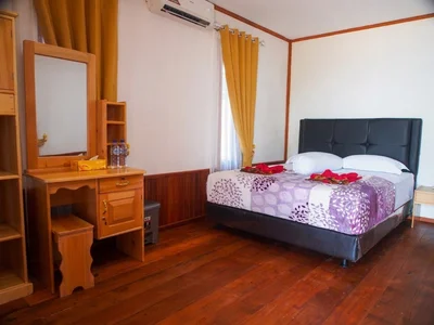 Spacious premium chalet interior with a large double bed and warm wooden paneling.