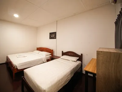 Standard room featuring twin beds, warm wooden paneling, and simple, practical furnishings.