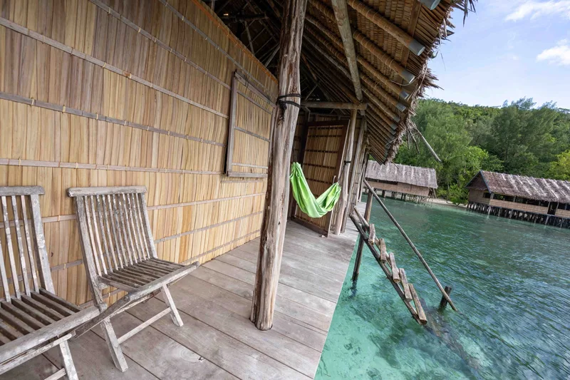 Private wooden balcony built directly over the turquoise Raja Ampat lagoon.
