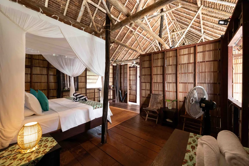 Simple and airy standard bedroom area with mosquito nets and natural ventilation.