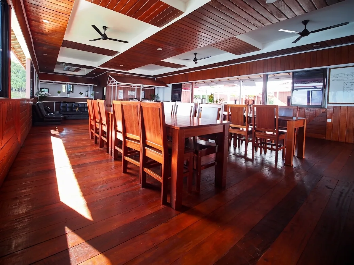 The dining hall, with a long timber table and a lounge area at the far end.
