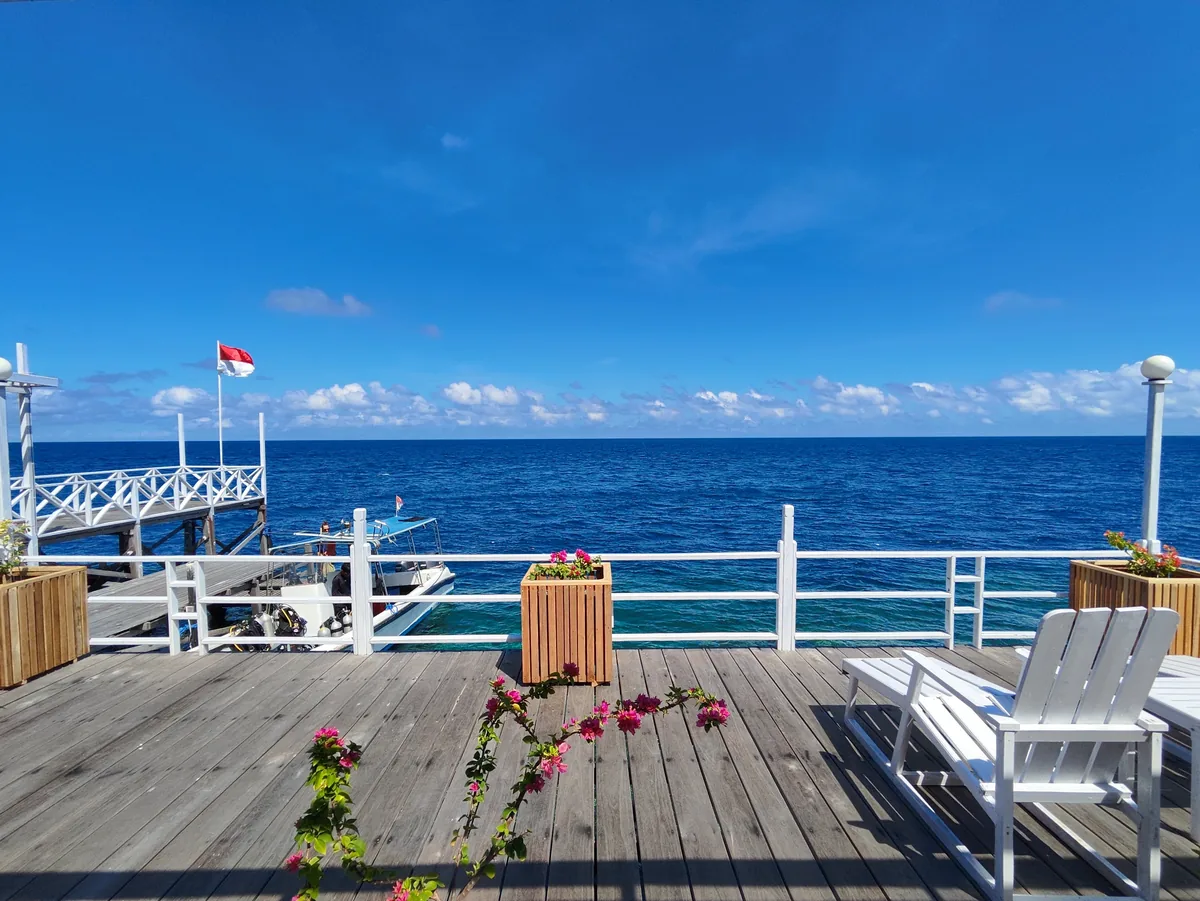White loungers on the deck above the jetty, with a dive boat moored alongside.