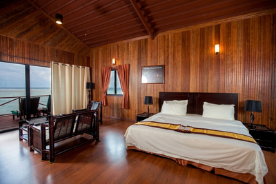 Exclusive Water Villa bedroom with expansive glass doors opening to the sea.