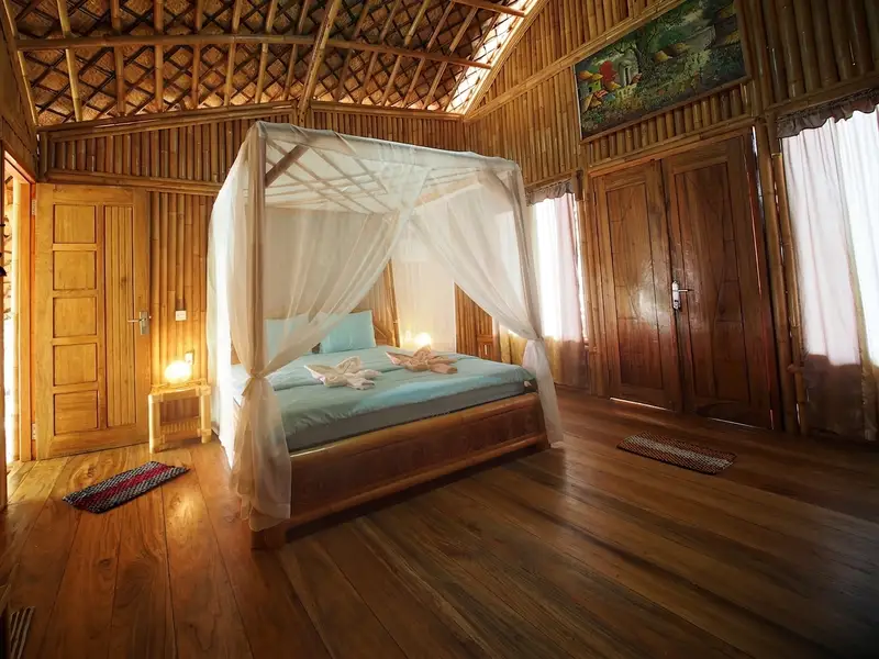 Comfortable bedroom area with natural bamboo walls, reflecting the resort's low-footprint philosophy.