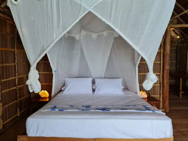 Spacious raised room featuring a comfortable double bed and mosquito net.